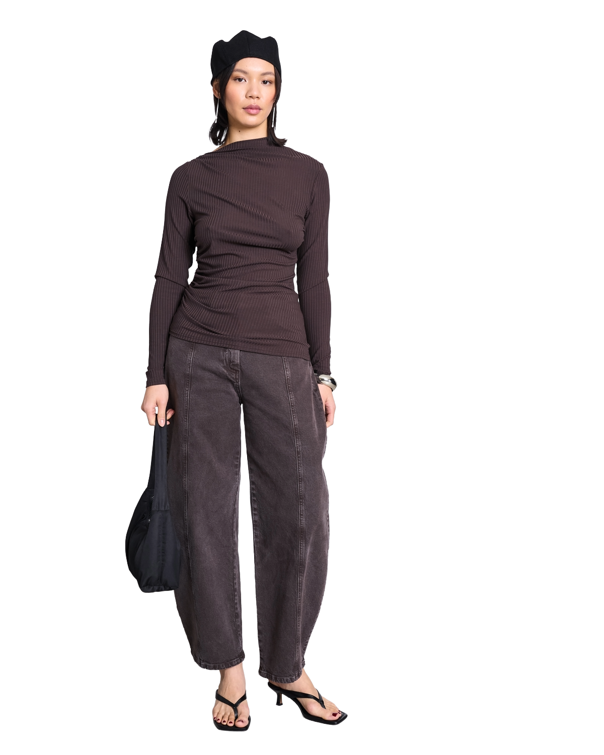 Woman wearing a sleeveless black crop top and high-waisted, wide-leg black pants with open-toe heels, walking confidently against a white background.