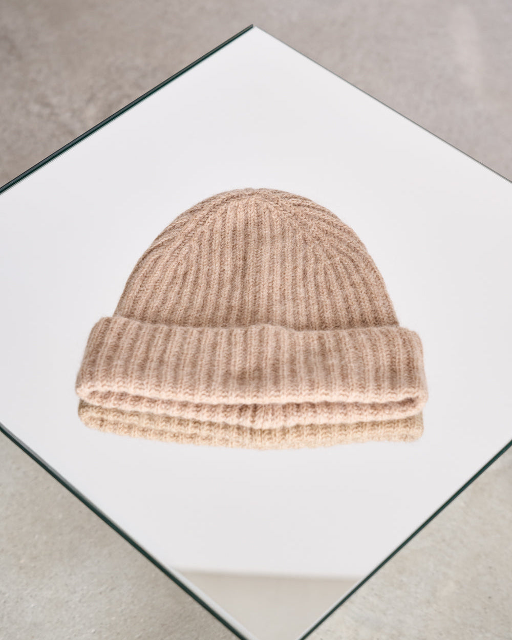 The jan-n-june WOOLY KNIT BEANIE BJON CAMEL, crafted from cozy mohair and wool with a folded brim, is displayed neatly on a square white surface with a reflective edge.