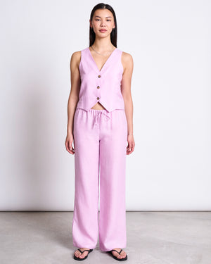 A woman stands against a white background wearing jan-n-junes LINEN DRAWSTRING PANTS SJOV in Light Orchid, paired with a matching sleeveless vest and black sandals.