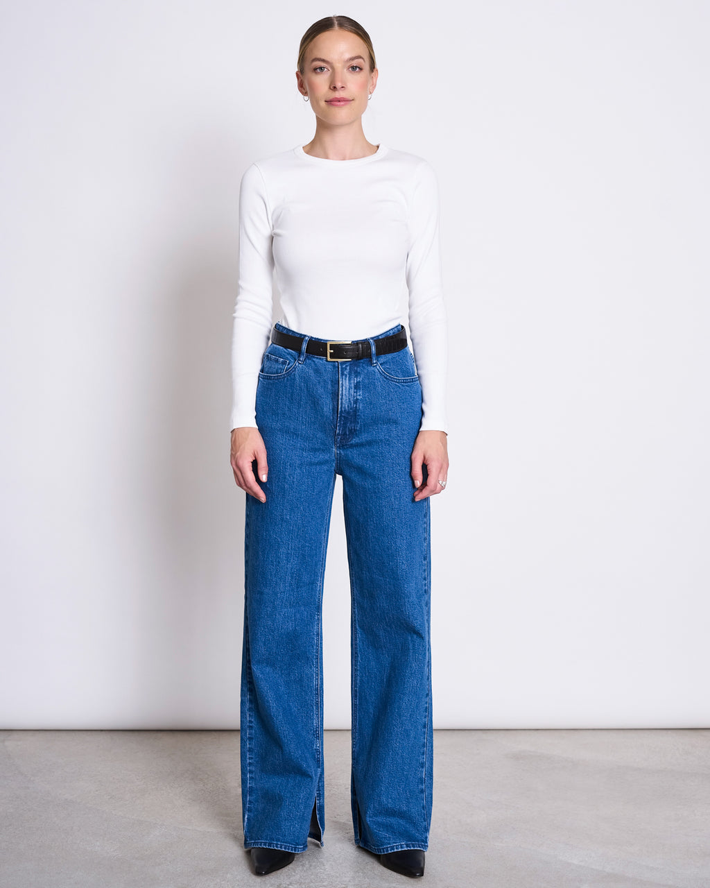 A woman stands against a plain background wearing the jan-n-june RIB LONGSLEEVE MURI WHITE GOTS, facing forward with a neutral expression to showcase this ideal layering piece.