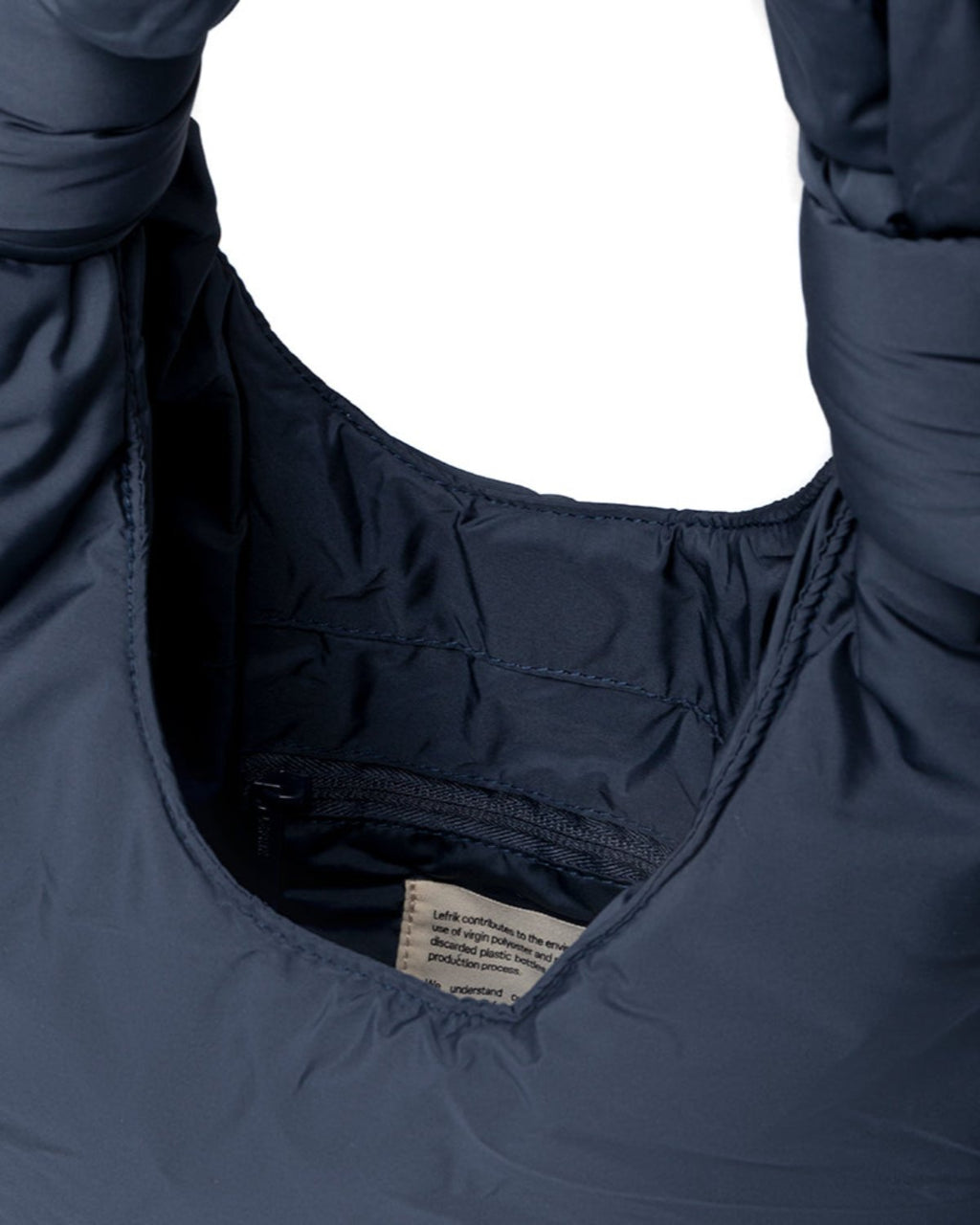 Close-up of the BAG BIWA PUFFY MINI MAIBON by jan-n-june, featuring a dark navy quilted RPET fabric with a padded collar and inner lining. The smooth, recycled material is both durable and stylish, with a visible white care label.