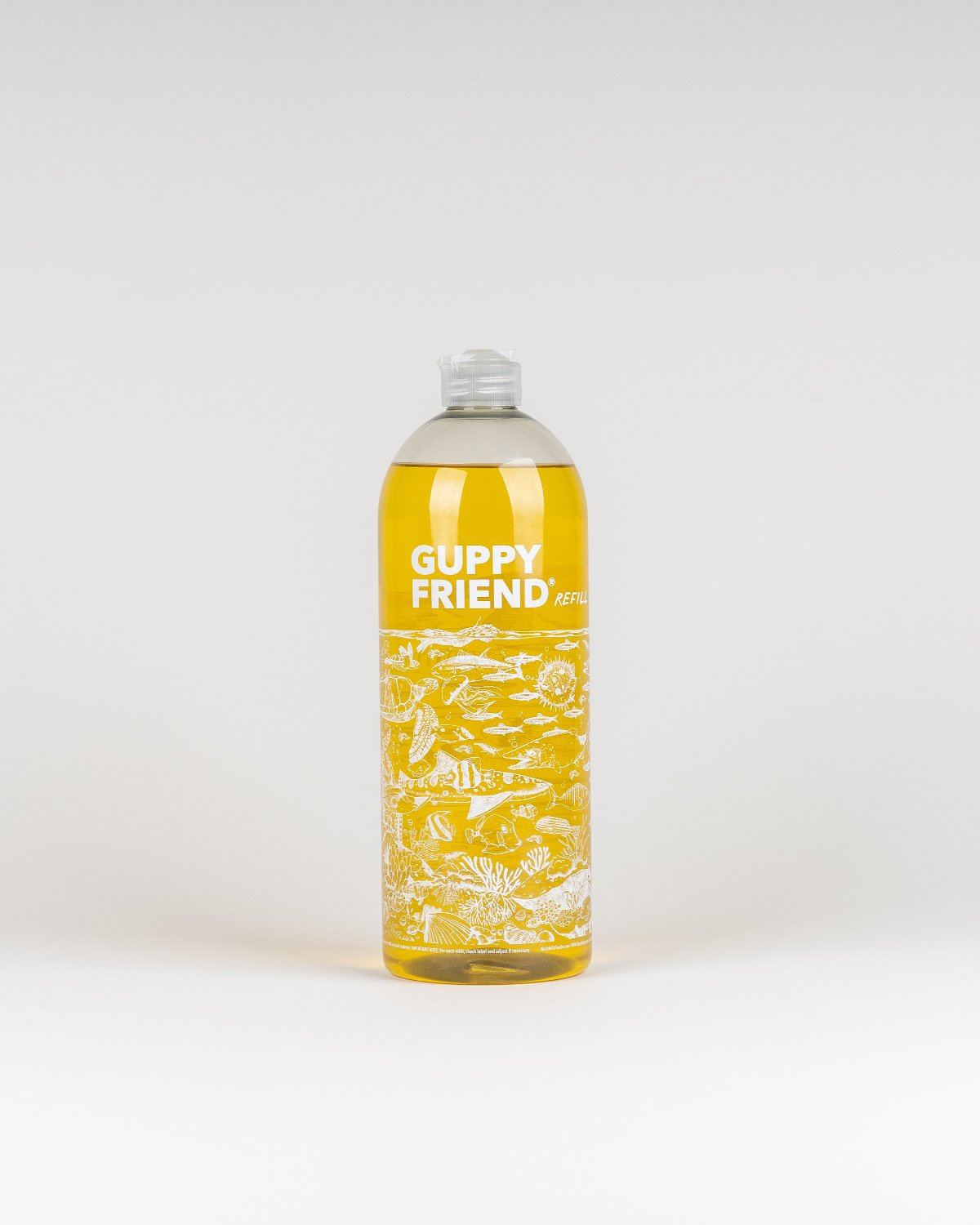 A clear plastic bottle of jan-n-june GUPPYFRIEND LAUNDRY DETERGENT, filled with yellow liquid and featuring white aquatic illustrations, stands upright against a plain white background. This vegan detergent is microplastic-free.