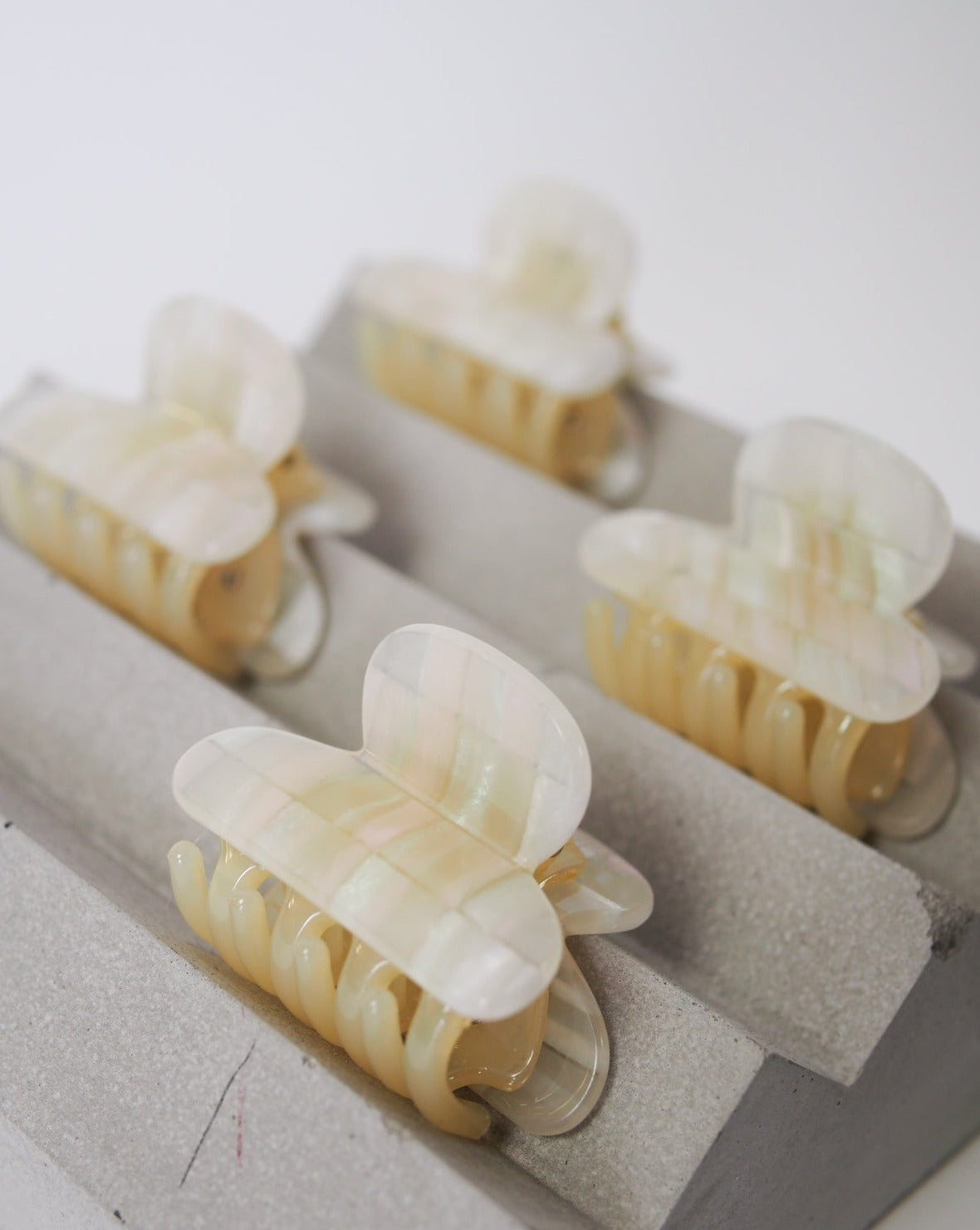 The MINI HEIRLOOM CLIP OPALITE SHELL CHECKER by jan-n-june features four pearly, checkered hair claws handmade in Italy from premium acetate. Stylish and sustainable, these cream-colored clips elevate any look.