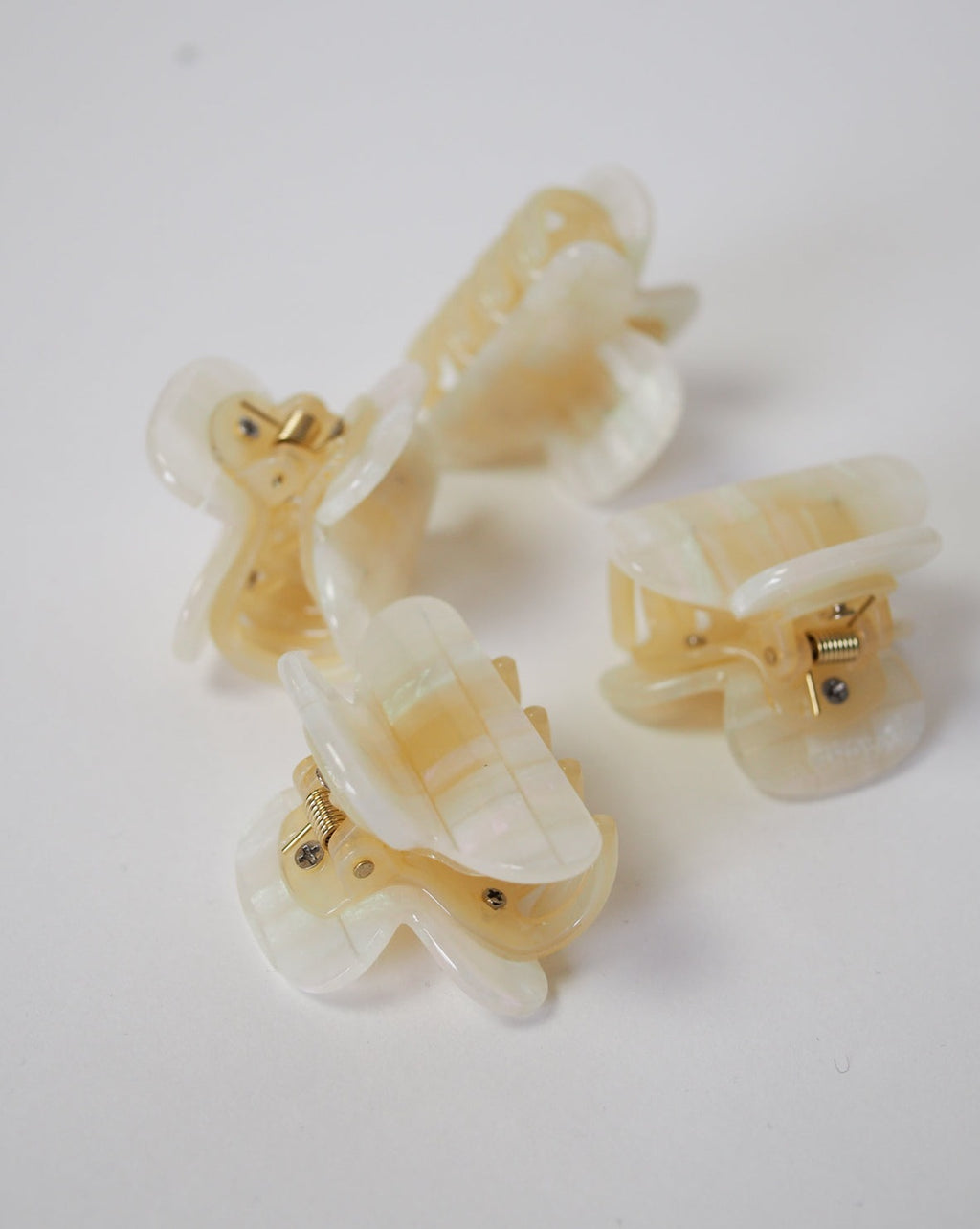Three MINI HEIRLOOM CLIP OPALITE SHELL CHECKER hair claws by jan-n-june, made in Italy from premium acetate with gold springs, are displayed on a plain white surface.
