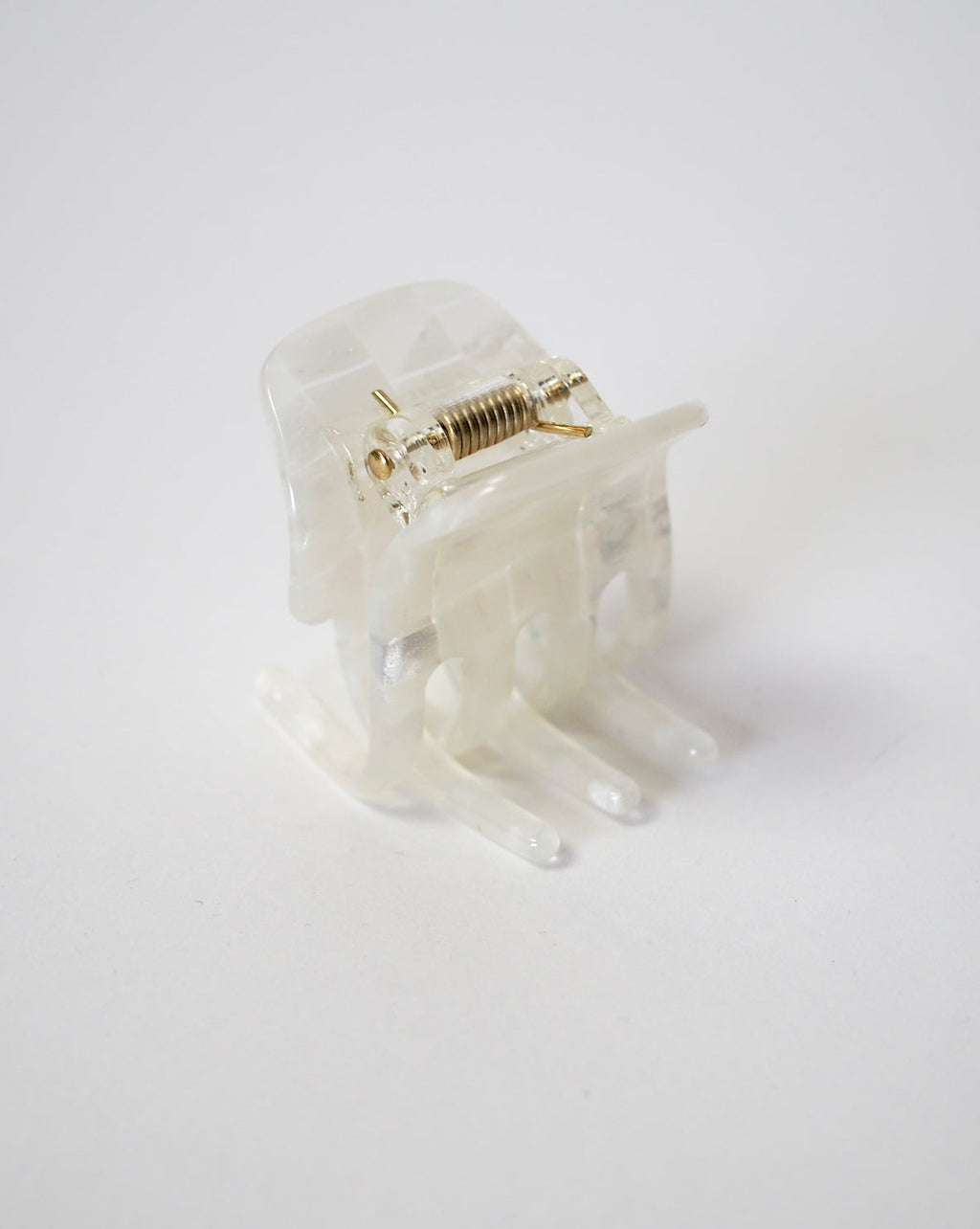 The jan-n-june MINI CLAW OPALITE SHELL CHECKER is a translucent plastic hair claw clip with a sturdy metal spring, handcrafted in Italy and shown on a plain white background.