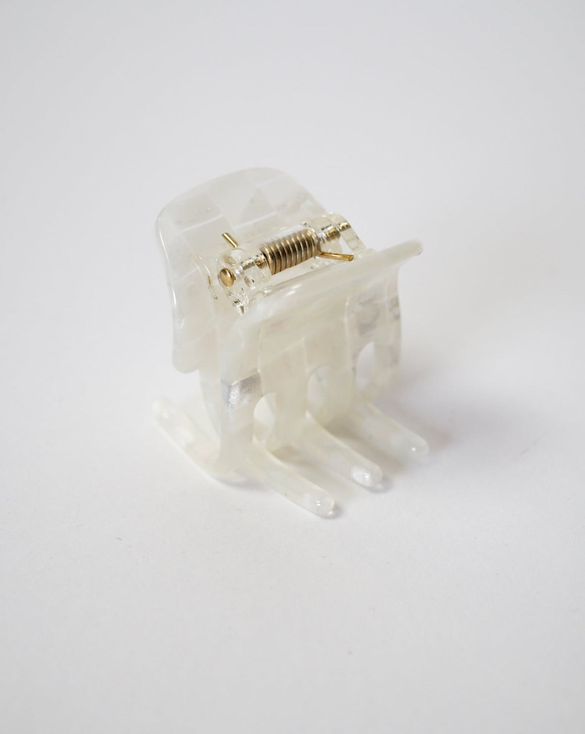 The jan-n-june MINI CLAW OPALITE SHELL CHECKER is a translucent plastic hair claw clip with a sturdy metal spring, handcrafted in Italy and shown on a plain white background.