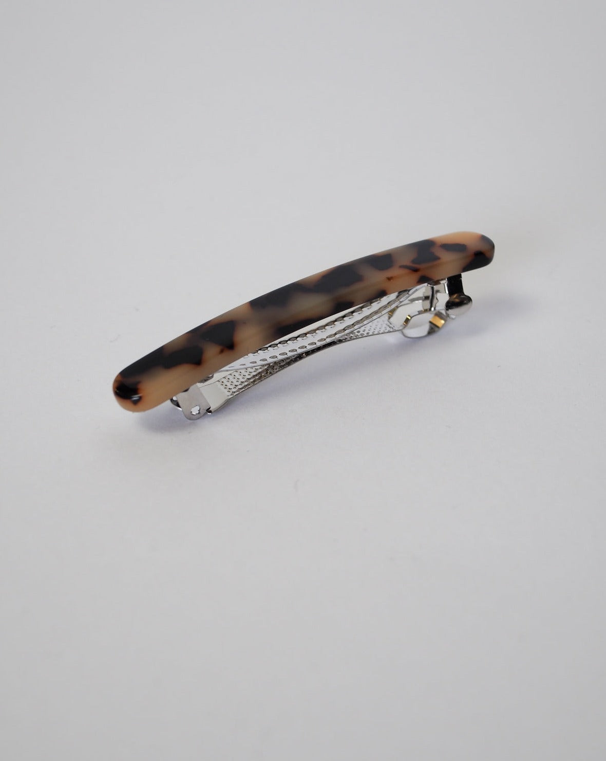 The MIDI PARIS BARRETTE BLONDE TORTOISE by JAN N JUNE features a silver metal clasp with a curved brown and black tortoiseshell-patterned Italian acetate top, shown against a plain light gray background.