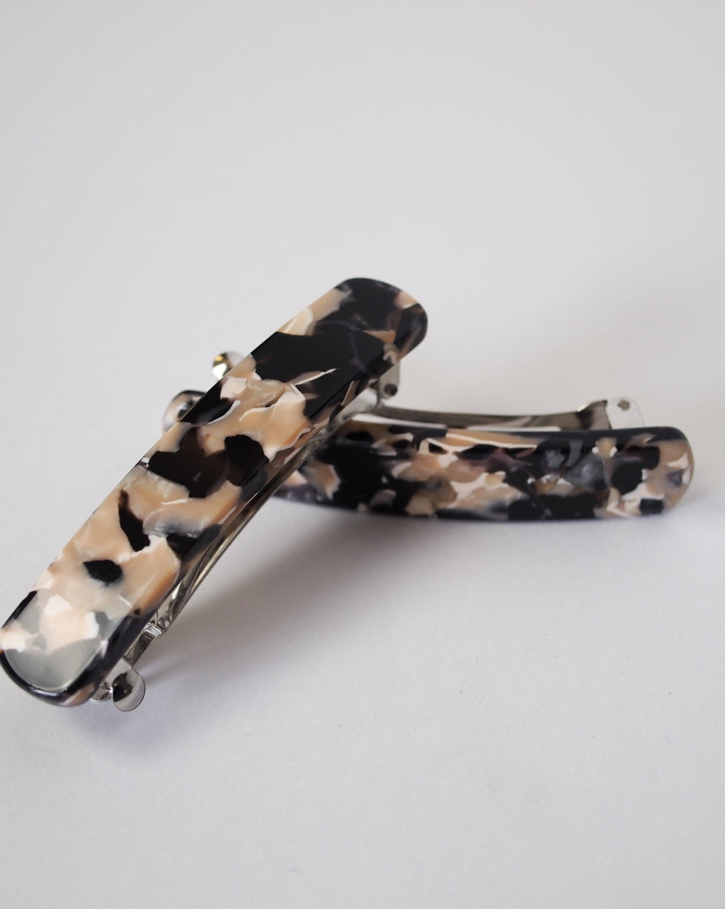 The jan-n-june HEIRLOOM BARRETTE ABALONE features two handmade rectangular hair barrettes crafted from heirloom-quality Italian acetate in marbled black, beige, and cream tones, shown resting on a white surface.