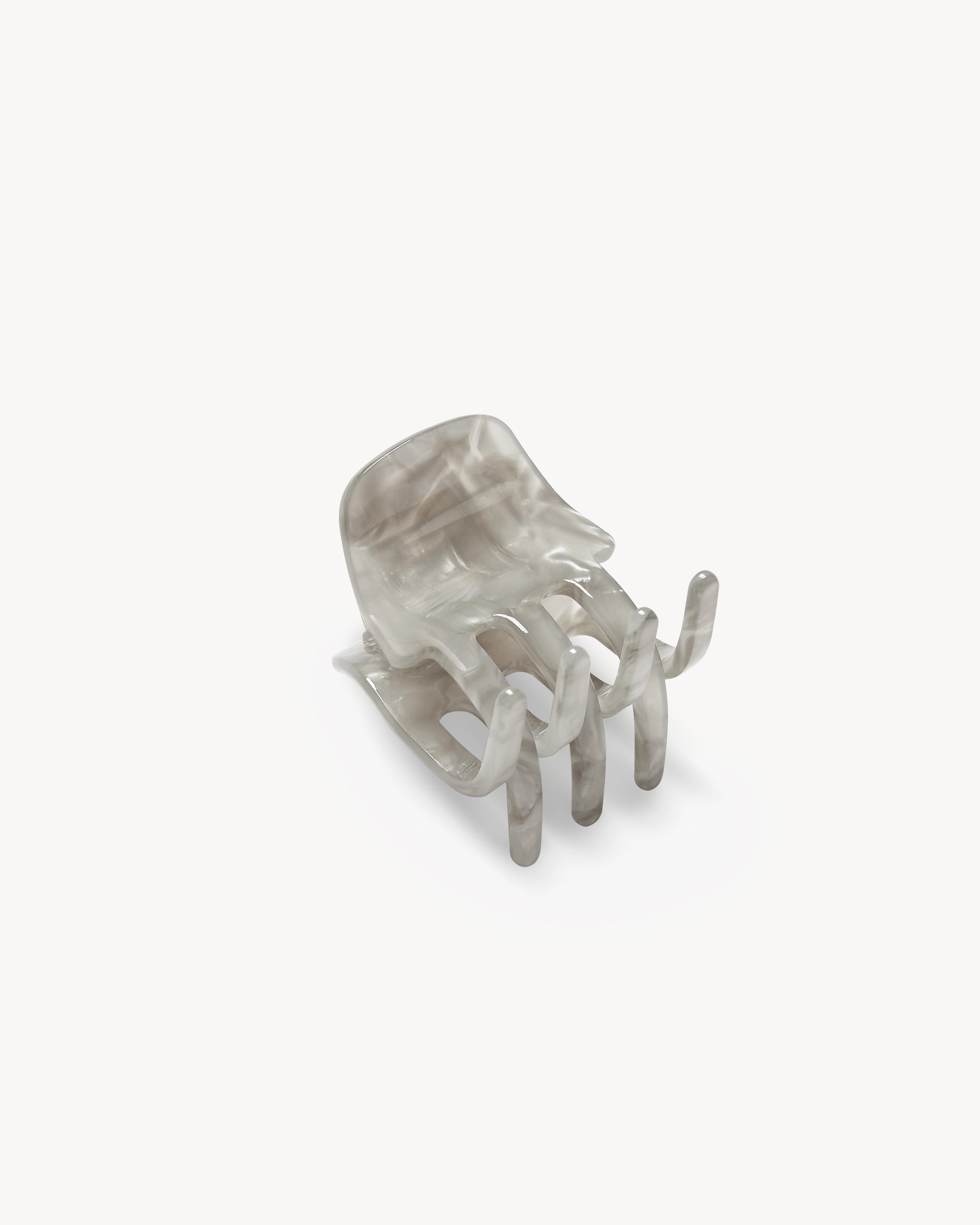 The MINI CLAW GREY SHELL by jan-n-june is a translucent gray chair, handcrafted in Italy, designed to resemble a human hand with spread fingers forming the seat and legs. Set against a plain white background.