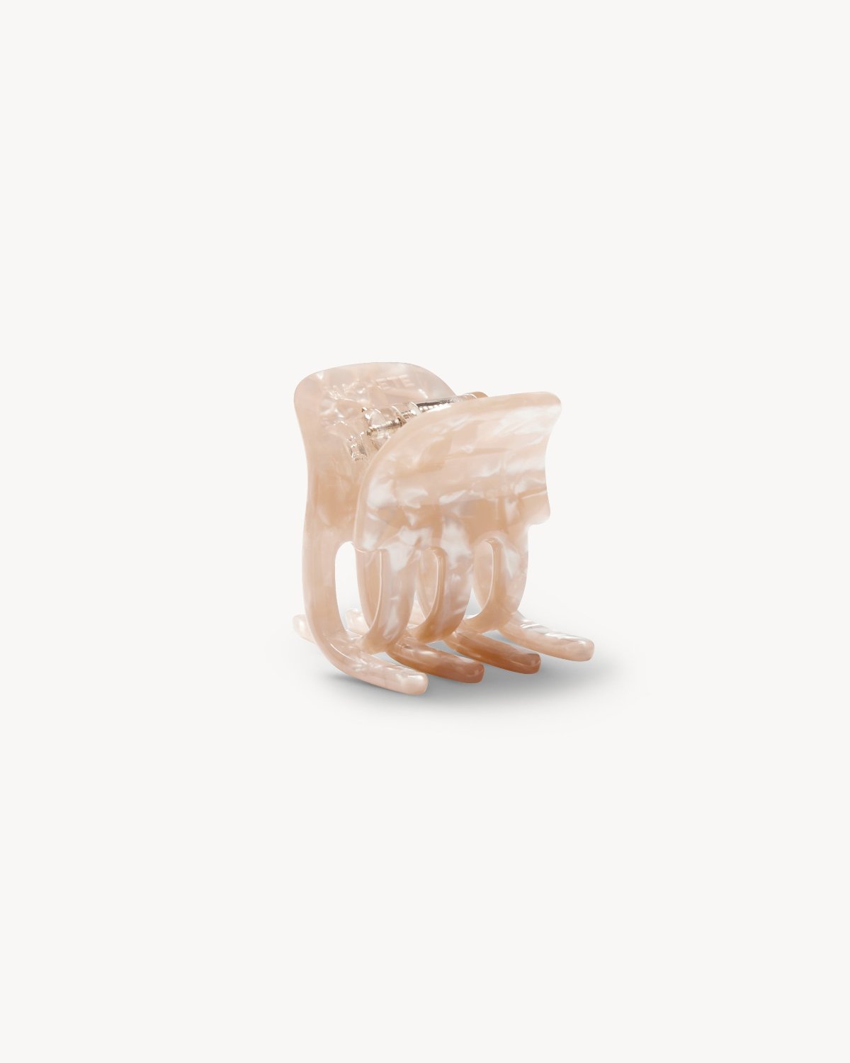 The jan-n-june MINI CLAW PEACH SHELL is a glossy, marbled beige acrylic hair clip with interlocking teeth, shown standing upright on a white background—ideal for adding style to any hairstyle.