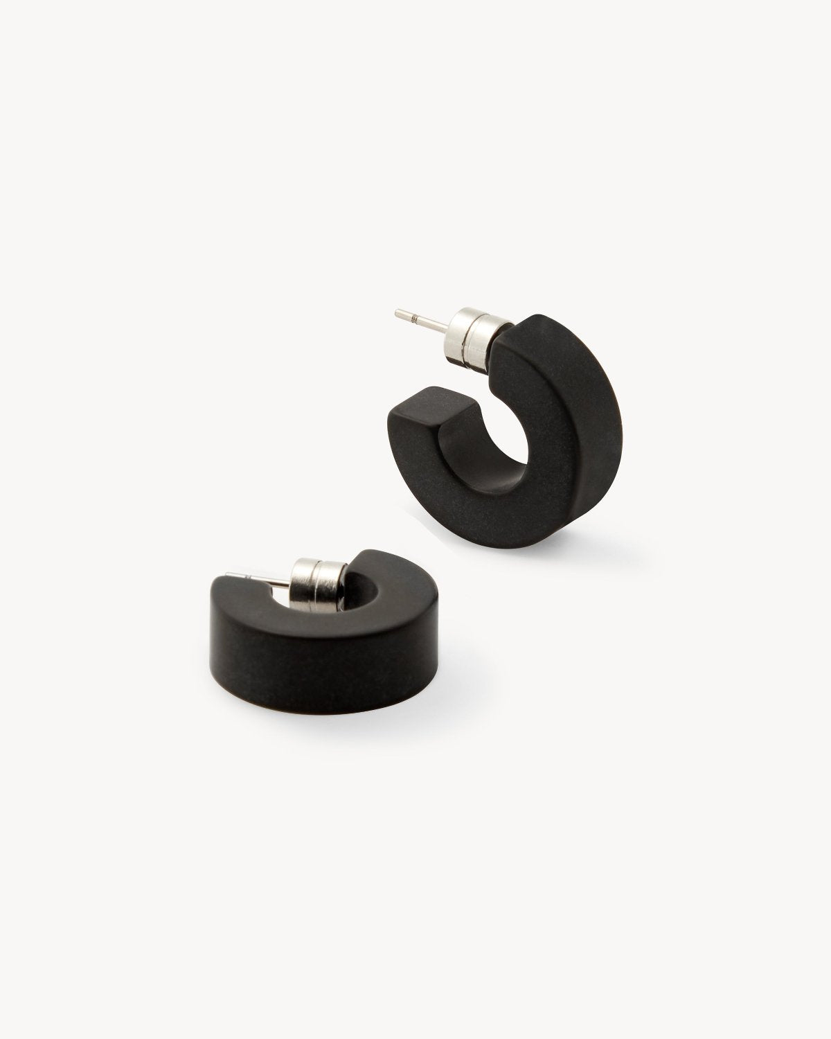 A pair of chunky, black matte MUSE HOOPS by jan-n-june with silver posts, displayed on a white background—sustainable earrings perfect for your everyday jewelry collection.