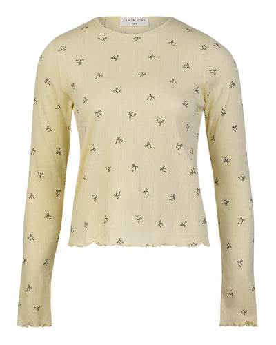 The jan-n-june POINTELLE PYJAMA CREWNECK BUTTERBOW GOTS is a light yellow crewneck blouse with subtle vertical ribbing, small black abstract patterns, and a gently ruffled hem and cuffs.