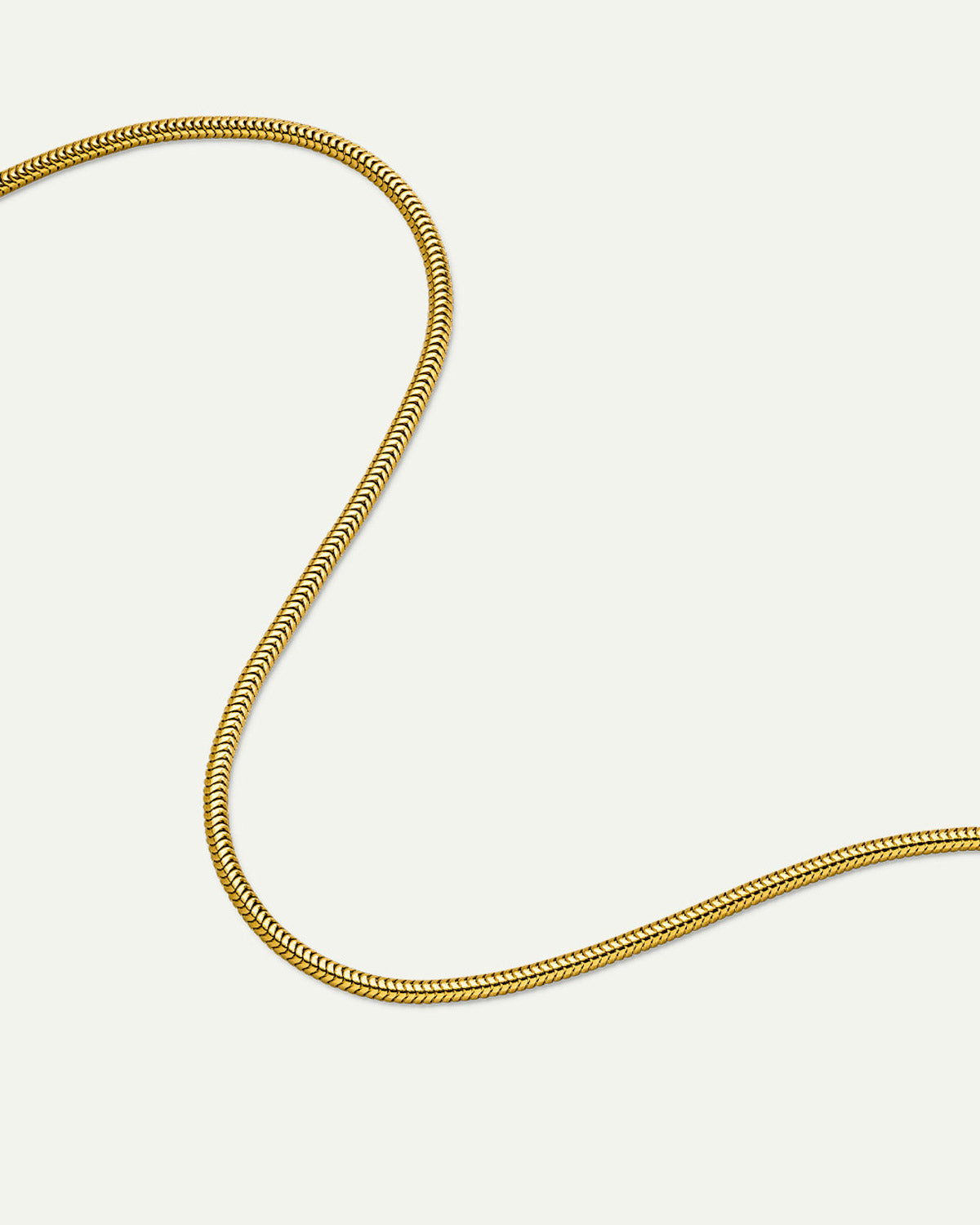 The jan-n-june DEAR DARLING BERLIN DELICATE SHORT SNAKE NECKLACE GOLD is displayed in a loose, flowing curve on a plain white background.