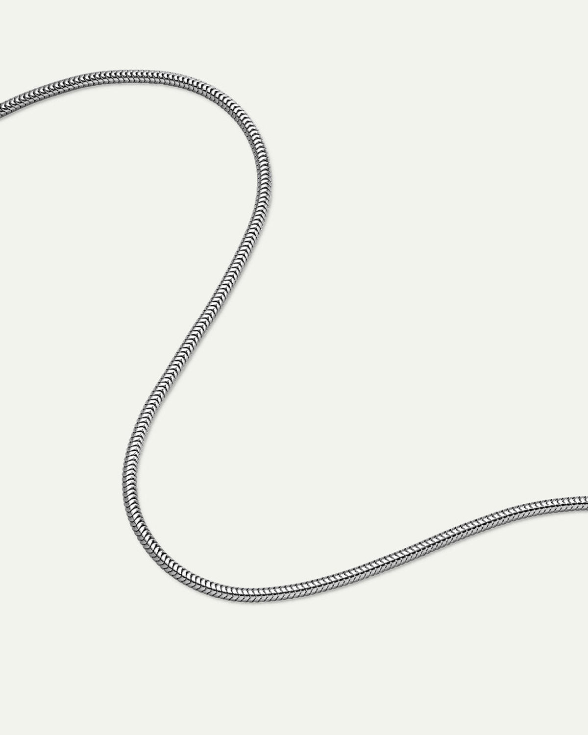 The DEAR DARLING BERLIN Delicate Short Snake Necklace Silver by jan-n-june, made from recycled 925 sterling silver, is displayed in a loose, curved S-shape on a plain white background.