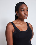 A woman with braided hair wears the jan-n-june MESH DETAIL TOP LLUVIA BLACK, styled with gold hoop earrings, as she looks slightly to the side against a plain white background.