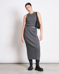Against a plain white background, a woman wears the jan-n-june KNIT TOP GARDA DARK GREY GOTS with a matching ribbed gray midi skirt, chunky black boots, and carries a black shoulder bag. Her hair is tied back and she accessorizes with hoop earrings.