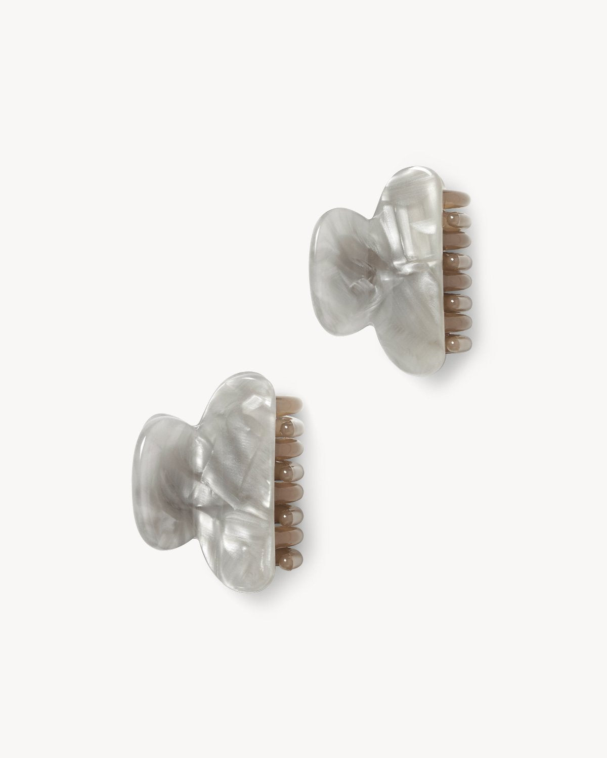 Two marble-patterned, light gray MINI HEIRLOOM CLIP GREY SHELL hair clips by jan-n-june, featuring a wavy design and beige teeth, handcrafted in Italy, are displayed on a white background.
