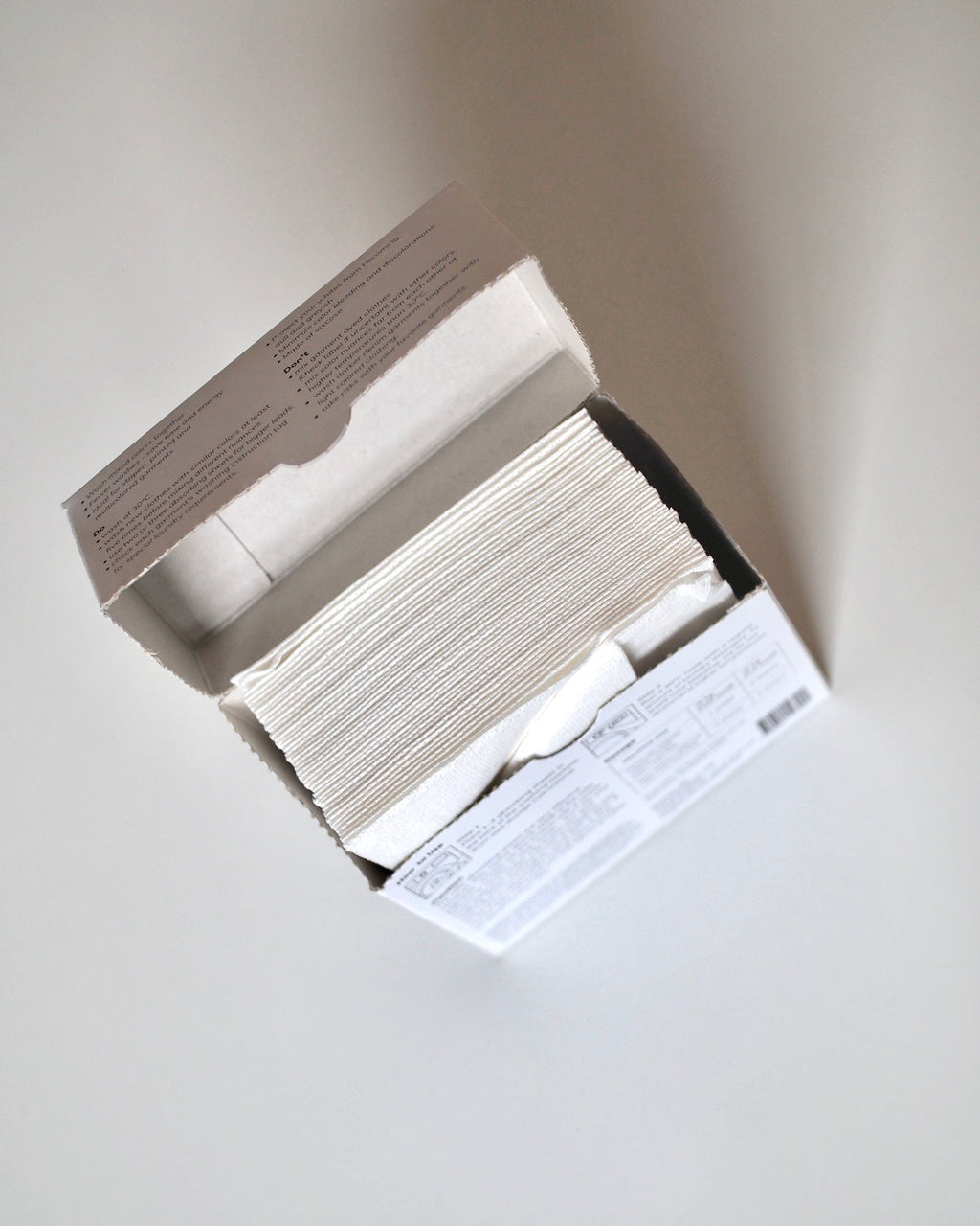 An open box of jan-n-june STEAMERY COLOR ABSORBER sheets is shown from above, with the individually stacked white sheets resembling laundry pieces, neatly arranged in the rectangular packaging for effective color run prevention.