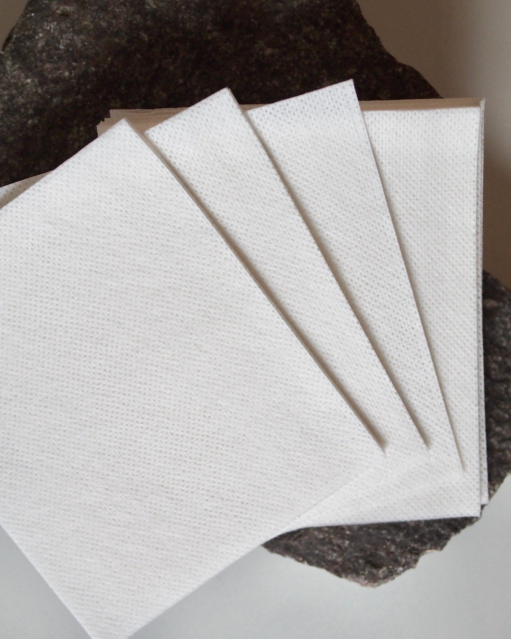 Four STEAMERY COLOR ABSORBER sheets by jan-n-june are fanned out on a dark stone surface, emphasizing their smooth texture and the color protection they offer against the rough, uneven background.