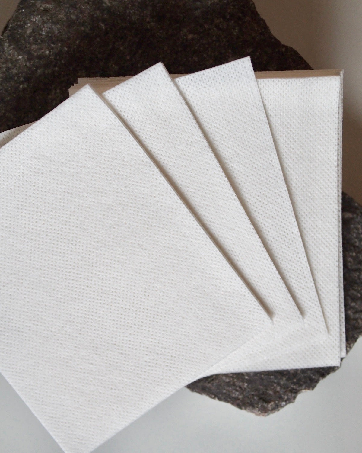 Four STEAMERY COLOR ABSORBER sheets by jan-n-june are fanned out on a dark stone surface, emphasizing their smooth texture and the color protection they offer against the rough, uneven background.