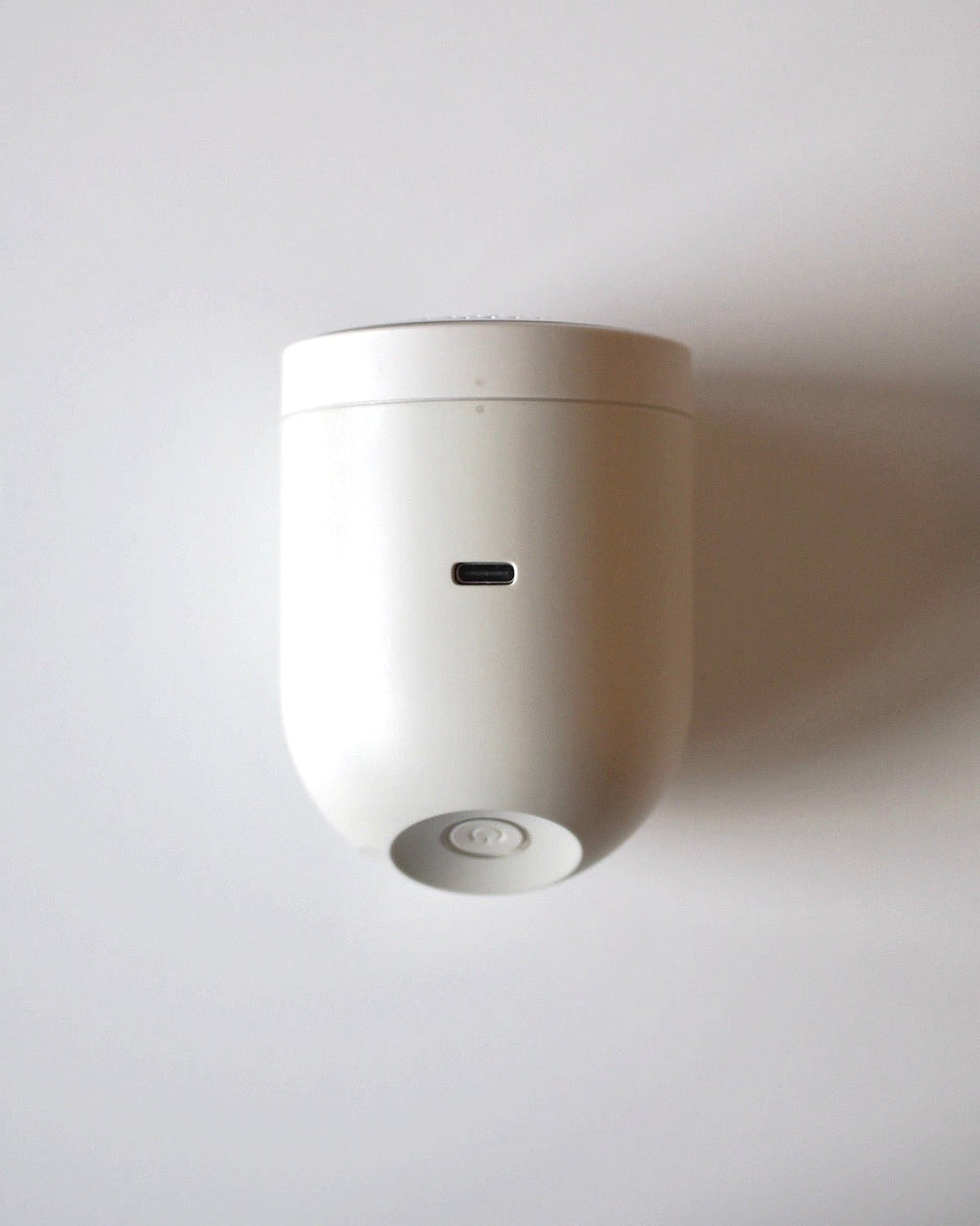 The jan-n-june STEAMERY PILO 2 SAND, a compact white fabric shaver with USB-C port and circular button, is mounted on a wall for easy access to precision blades that ensure effective lint removal.