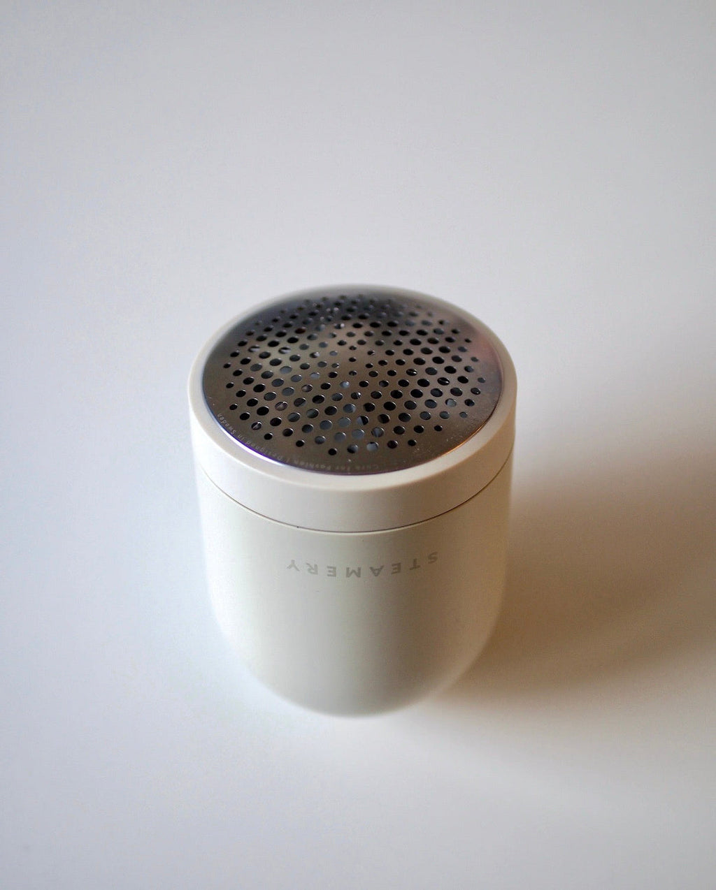 A compact, cylindrical fabric shaver—STEAMERY PILO 2 SAND by jan-n-june—with a metallic perforated top, sits on a plain white surface.